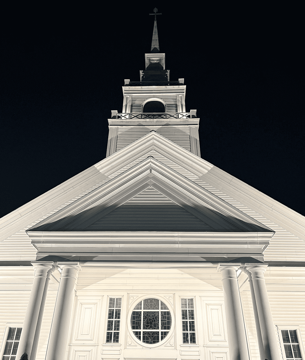 Illuminated church steeple at night with clear architectural details.